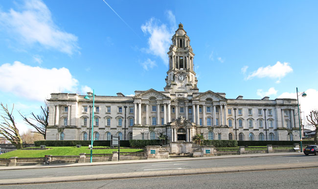 An image of the front of Stockport Town Hall with a blue sky in the background