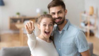 couple in their new home. Woman holding up new keys.
