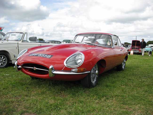 An image of a red Vintage Jaguar in a field 