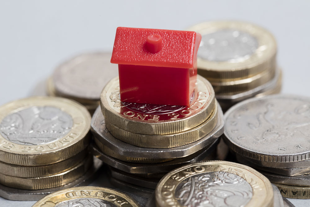 pound coins with small plastic red house 
